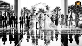BANGKOK — A black and white image captures a wedding ceremony at the Four Seasons Bangkok. The reflection of the bride, groom face-to-face, and bridal party is visible on a glass floor.